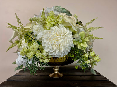This gorgeous centrepiece is a delicate symphony of white and cream roses and huge pom pom dahlias interspersed with chartreuse hydrangea, orchid buds and green hypericum berries