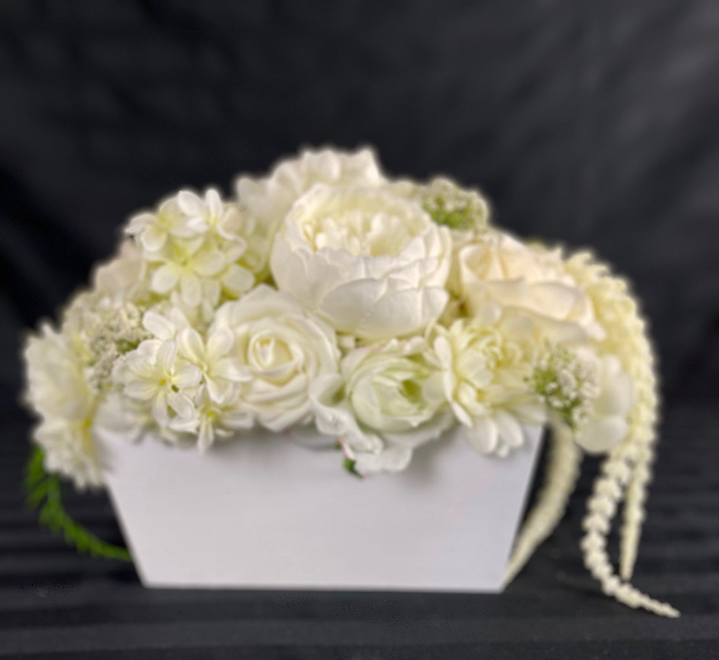 Bring a timeless elegance to your wedding guest tables with these centrepieces from the in Buttercream collection. Crafted with all ivory flowers, including hydrangea, dahlia and roses, and dangling amaranth all nestled into&nbsp; &nbsp;a simple white rectangular wood box, these arrangements provides a perfect blend of simplicity and beauty. This simple centrepiece is a great value for any budget