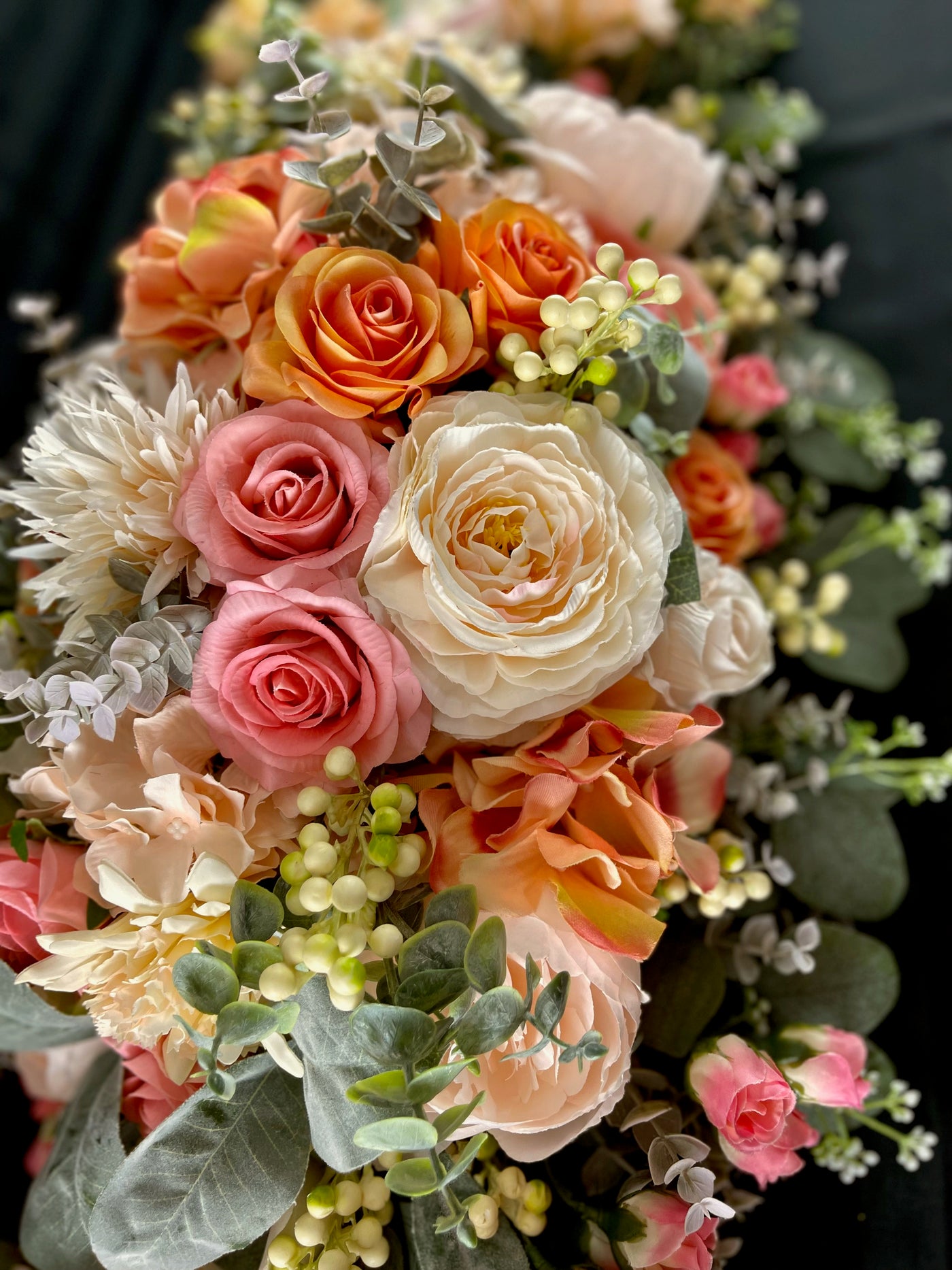 Four foot long casket spray made up of peach, apricot , and dusty pink  assorted flowers accented by sage eucalyptus.