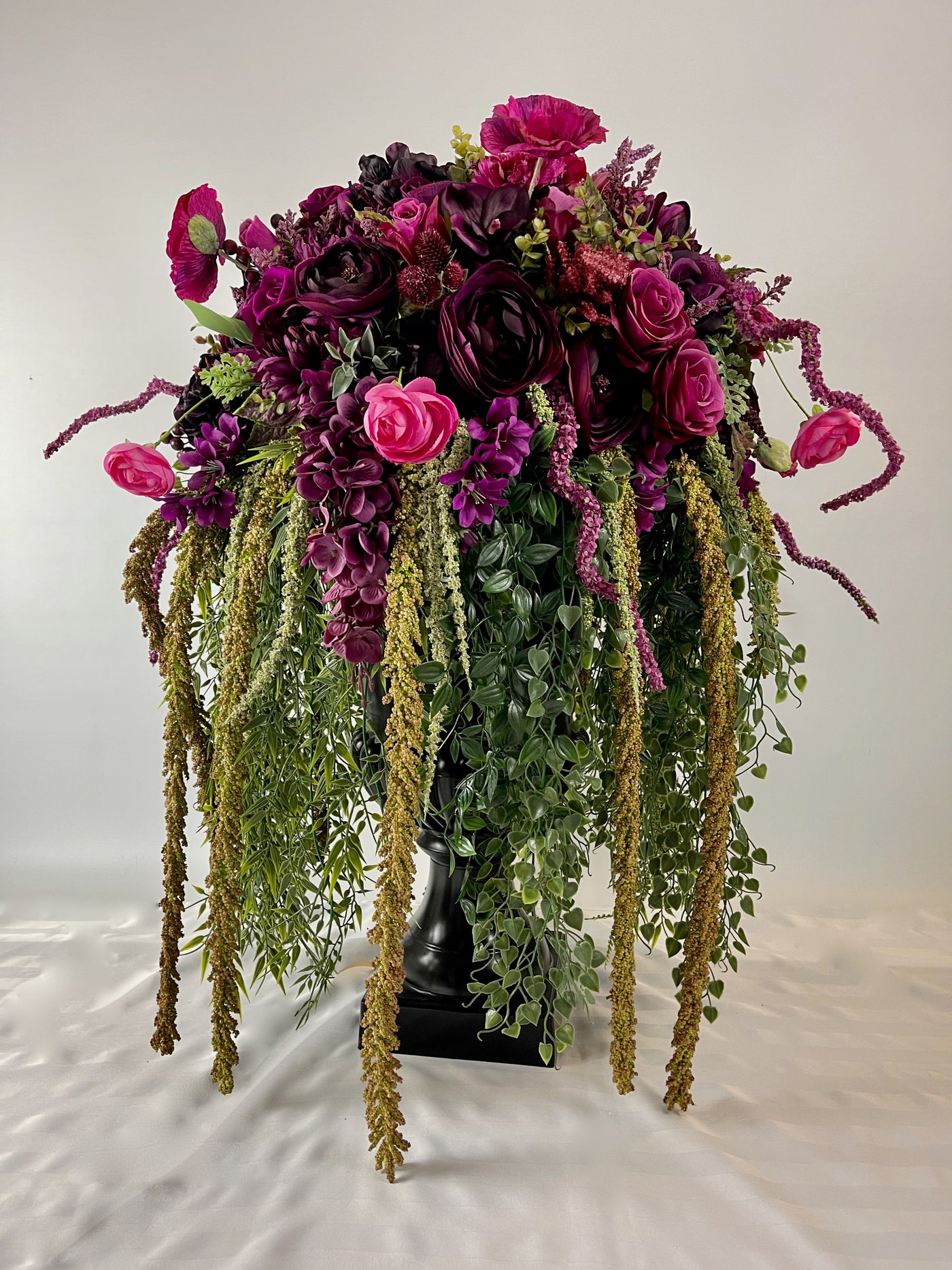 Make a bold statement with this 3 foot tall black planter overflowing with rich magenta blooms and cascading greenery.