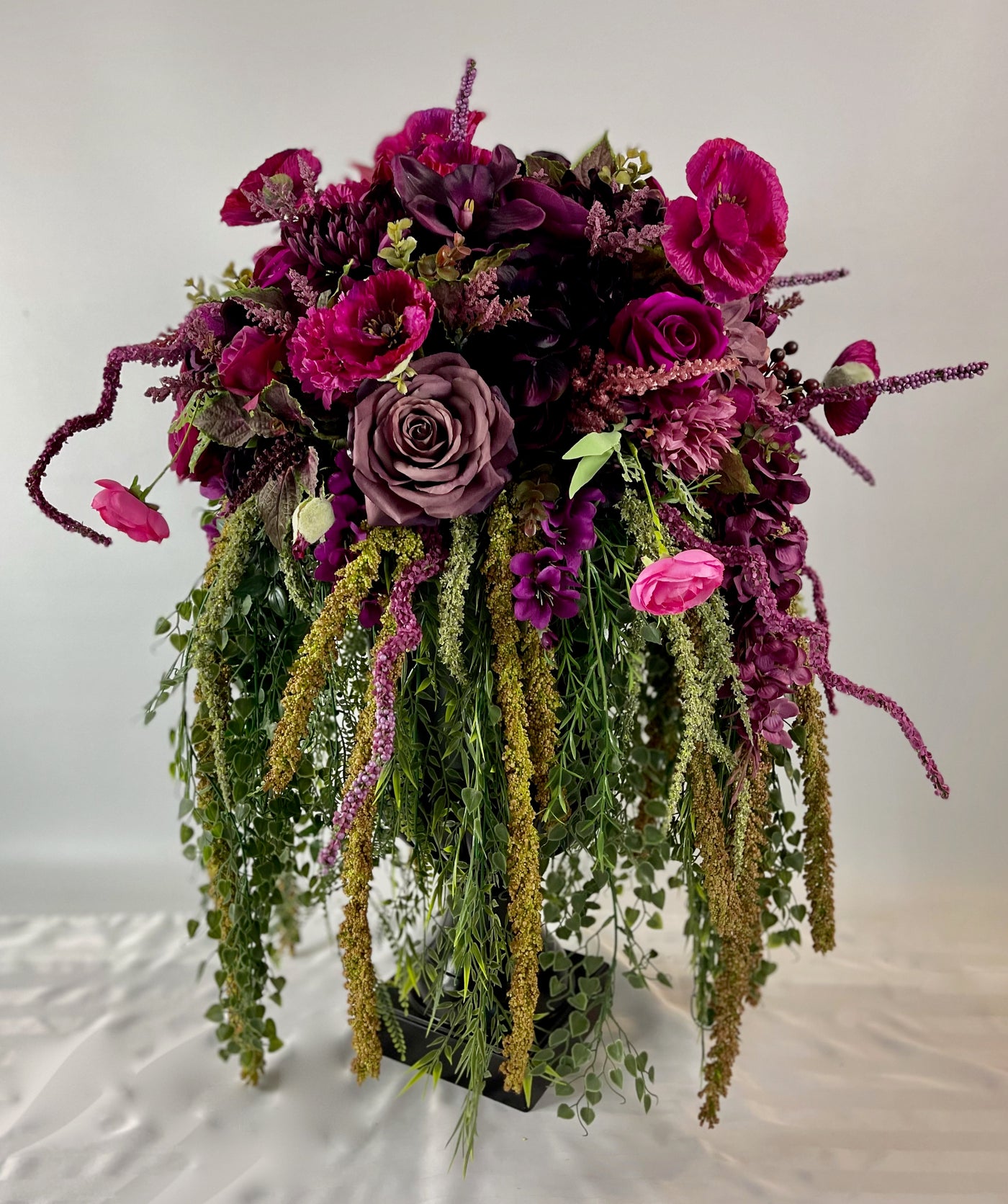 Make a bold statement with this 3 foot tall black planter overflowing with rich magenta blooms and cascading greenery.