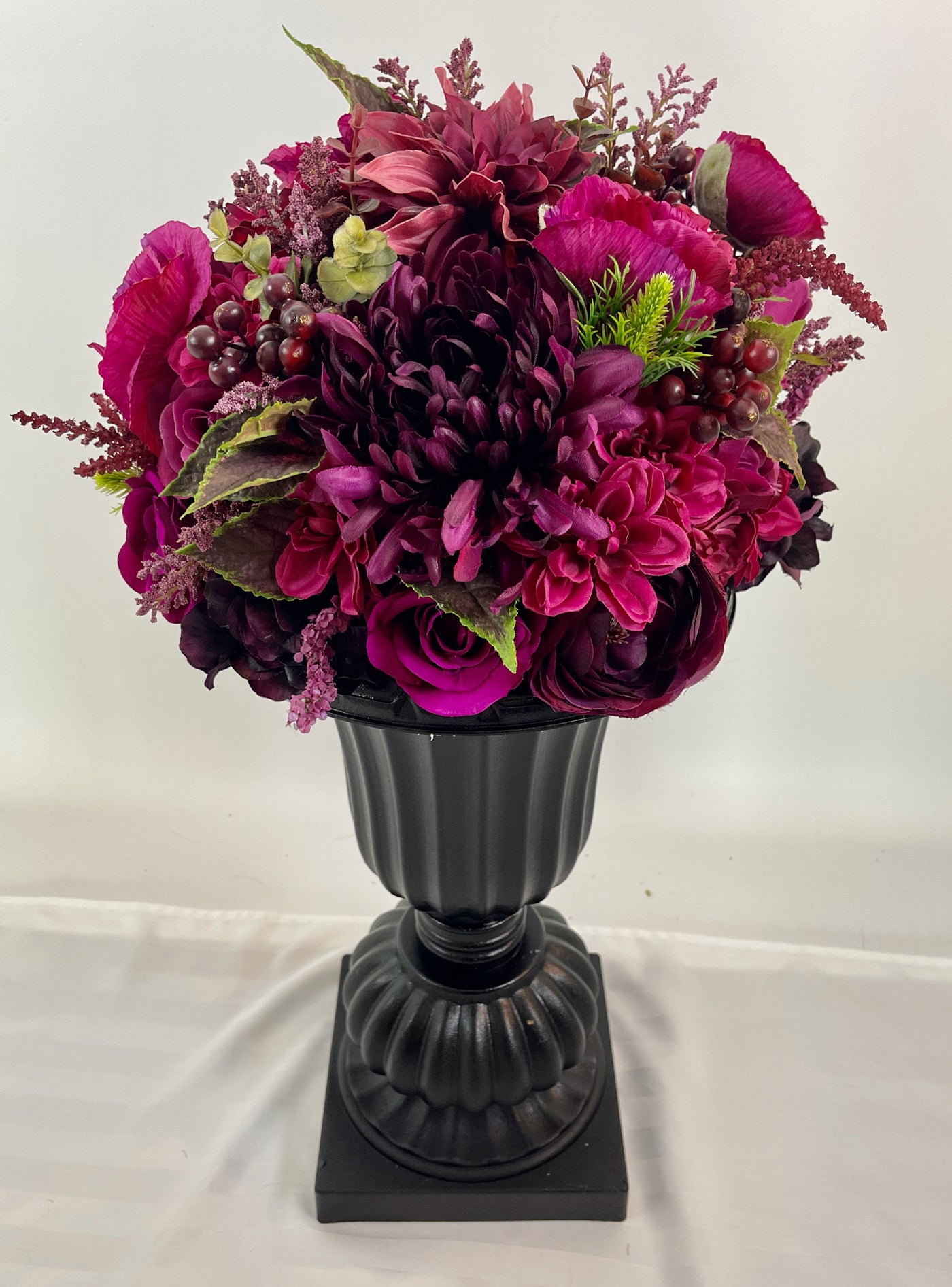 Elevating any space with its height of 2 feet 4 inches, this sophisticated black planter boasts an abundance of opulent magenta blossoms. 