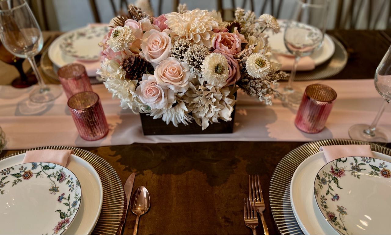 This soft-toned cream, blush and rich brown centrepiece features earth elements such as pine cones and chocolate brown pincushions. This earthy heartiness is juxtaposed with the delicate petals of large pompom dahlias, cream sunflowers, blush floribunda roses, champagne hydrangeas, and accented with cream snowberries.&nbsp; This Bohemian inspired creation is presented in an espresso stained wood box (L8”x W4”x H4”).