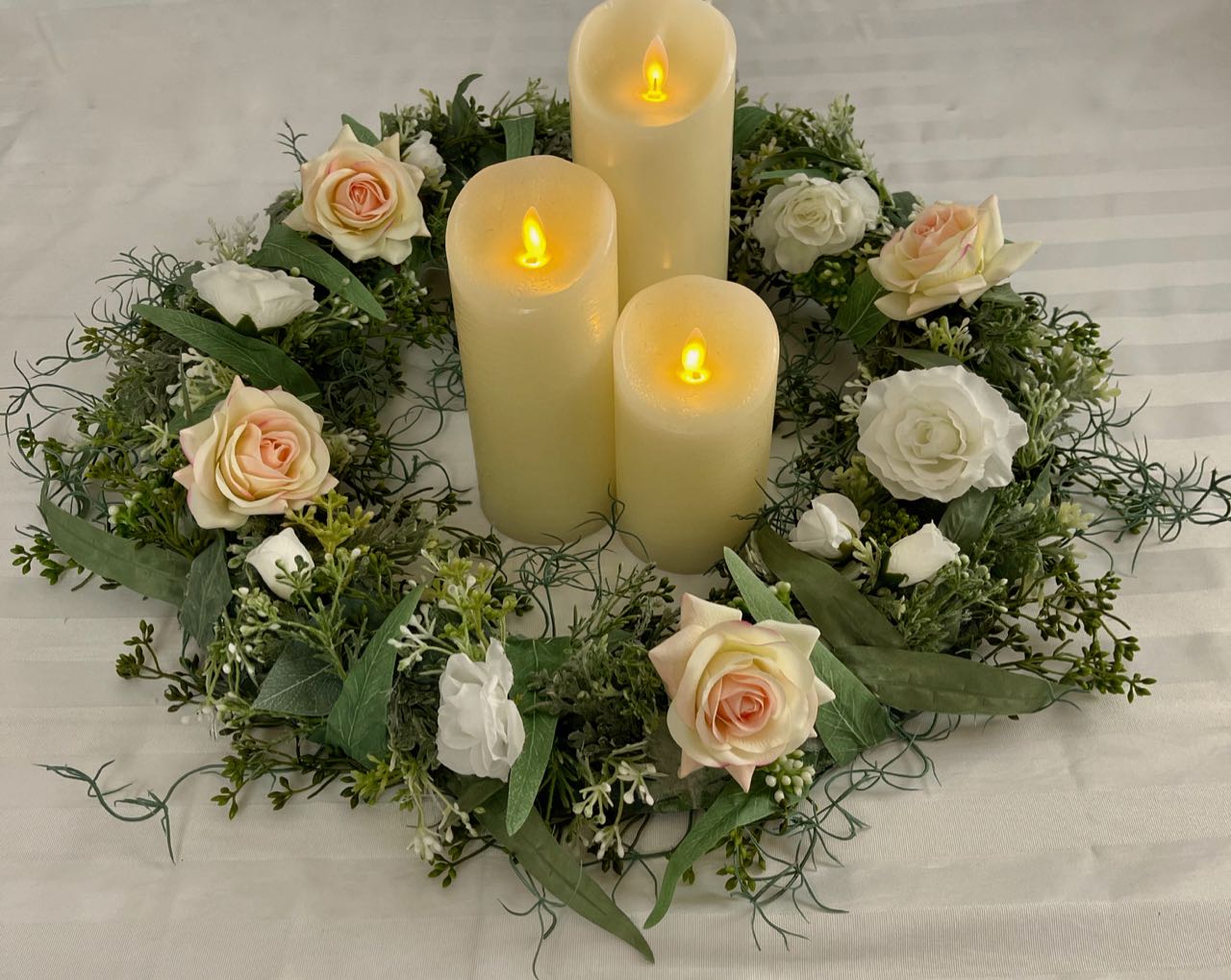 Eucalyptus Candle Ring. Meticulously crafted with five types of sage eucalyptus, four blush roses and a splash of mini white roses, its 21-inch circumference and 10-inch inner circumference combine stately beauty with a luxurious feel.