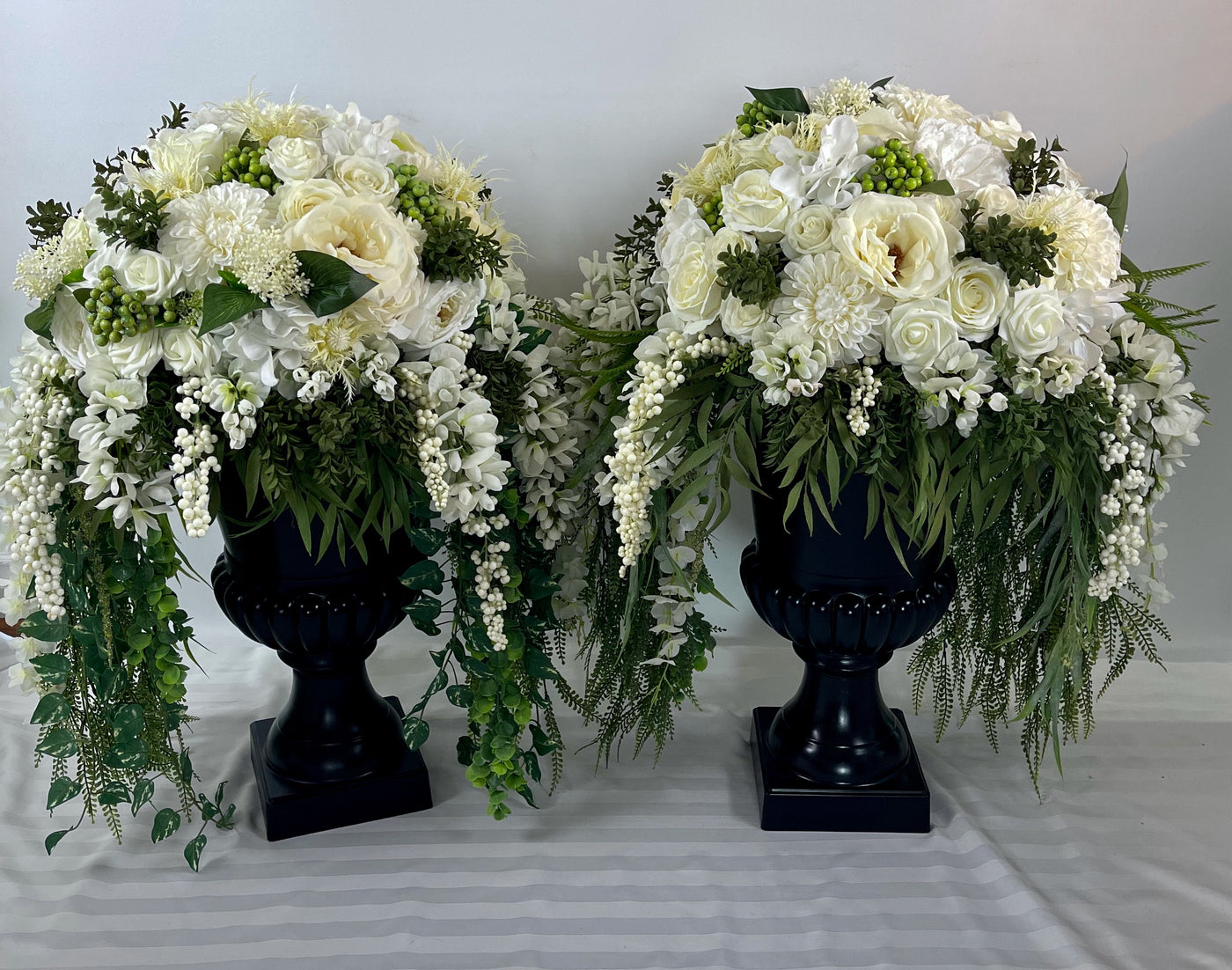 Three foot tall black urn with cascading white flowers and greenery- two availabe