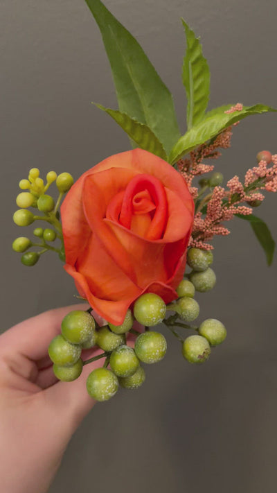 A single dramatic orange rose coupled with green hypericum berries and peach tree leaves wrapped in a burlap ribbon.