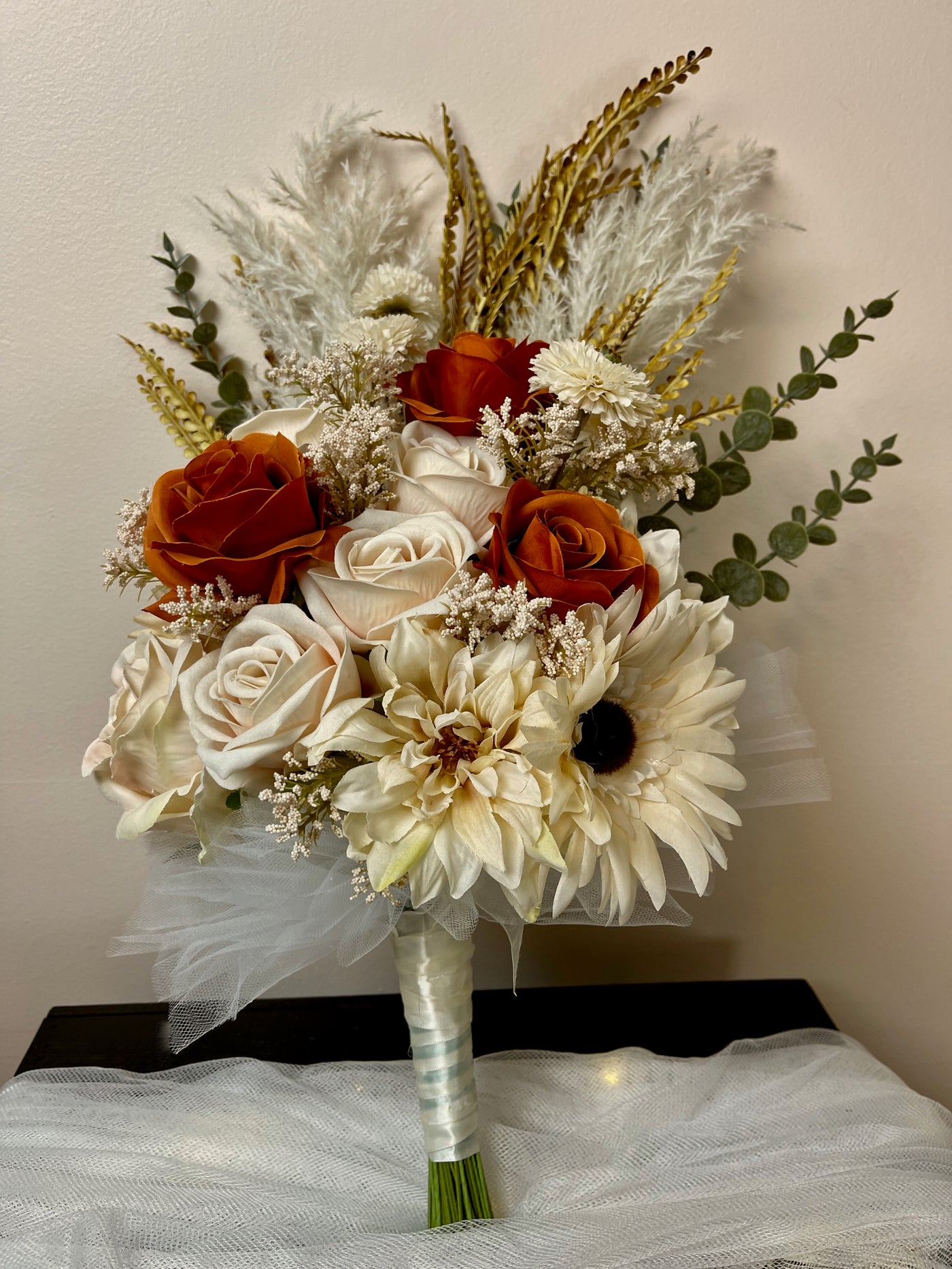 Side held Bridesmaid bouquet with cream pampas, eucalyptus, cream sunflowers and roses interspersed with a beautiful pop of color from a trio of rust roses. Five day rental $59.00