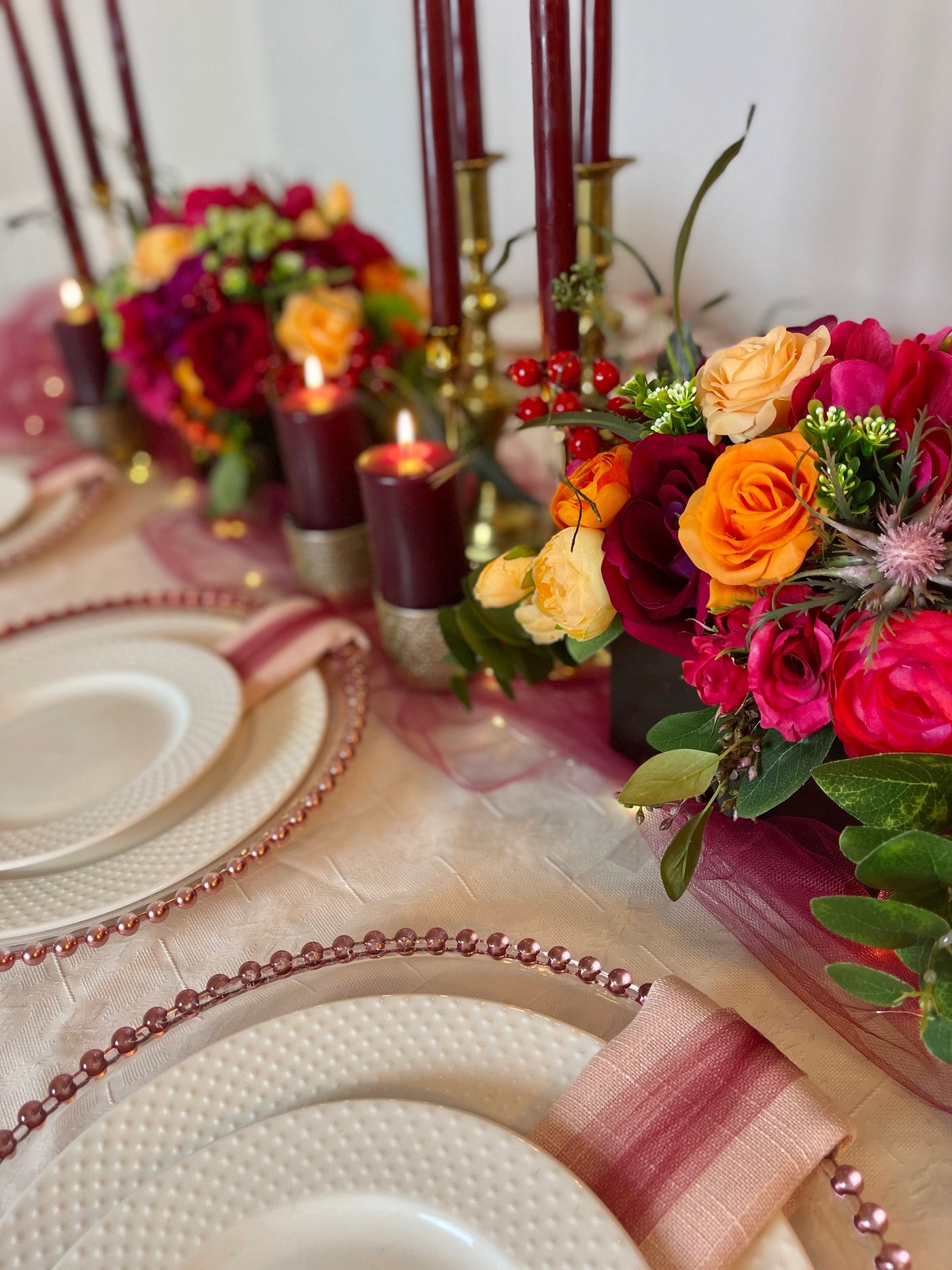 Rent a Rose- Centrepiece- Orange, Burgundy, and Fuchsia- flowers with Olive green berries rent for five days for $54.00.
