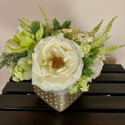 Roses in cream, ivory and white are combined effortlessly with green hydrangea, orchids and astilbe. This exquisite arrangement is accented by olive hypericum berries&nbsp;and thistle to create a perfect centrepiece for a high top cocktail table. This lovely arrangement is 5 inch x 5 inch and sits in a concrete vase accented at the bottom with gold foil.