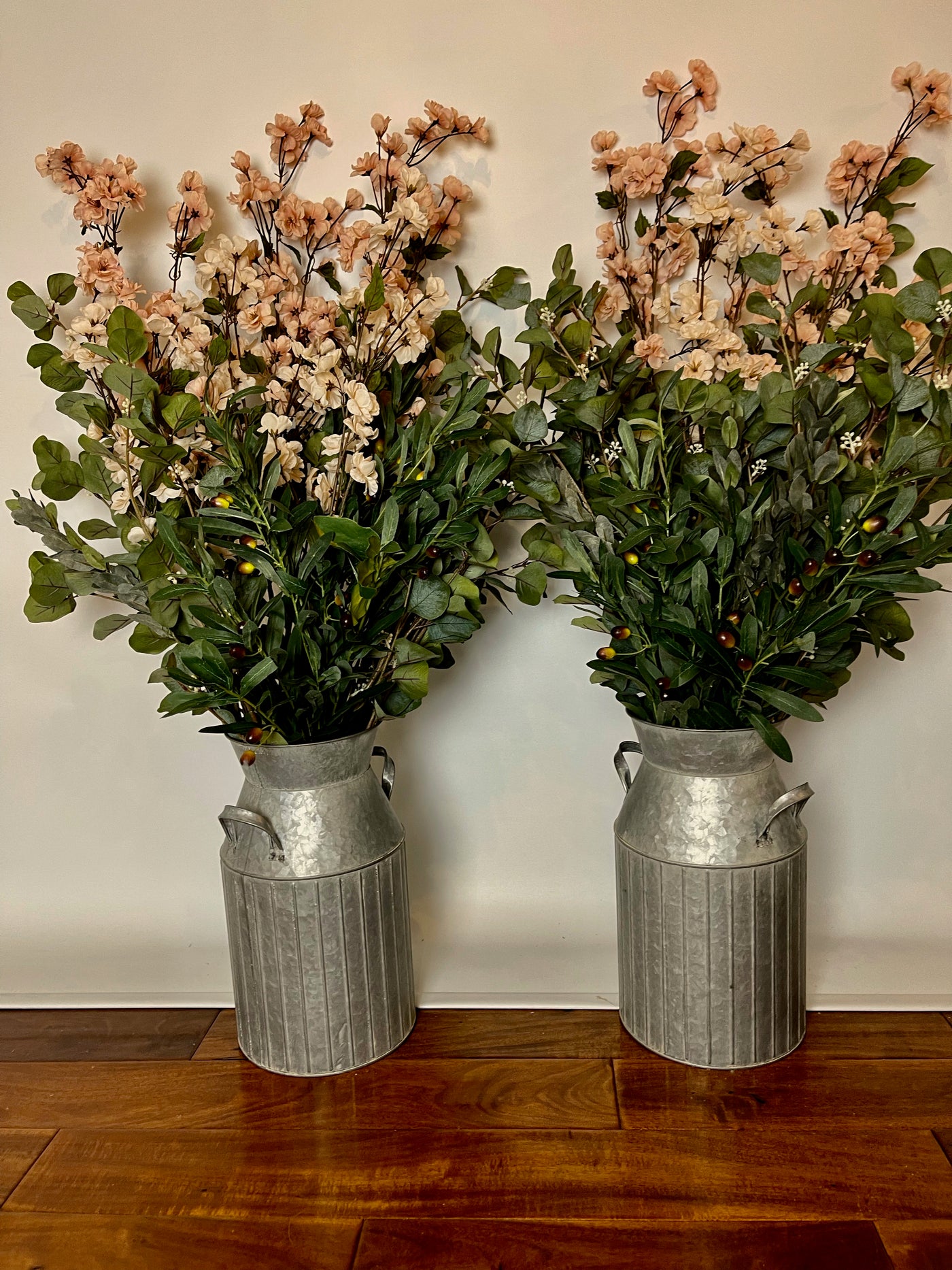 These two galvanized steel milk containers can come filled with either eucalyptus accompanied by small beige and pale pink flowers, or eucalyptus alone. Containers are 15" tall, and with the florals are 36" tall.