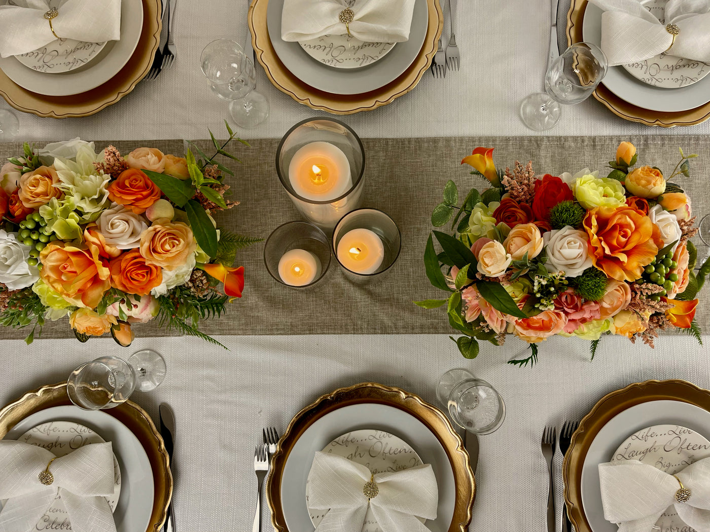  Ornate gold chargers shown on a white tablecloth with with white napkins and gold napkin rings