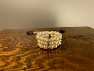 Elegant napkin ring comprised of three stands of pearls with a silver clasp studded with diamonds holding them together. Rent for $.25