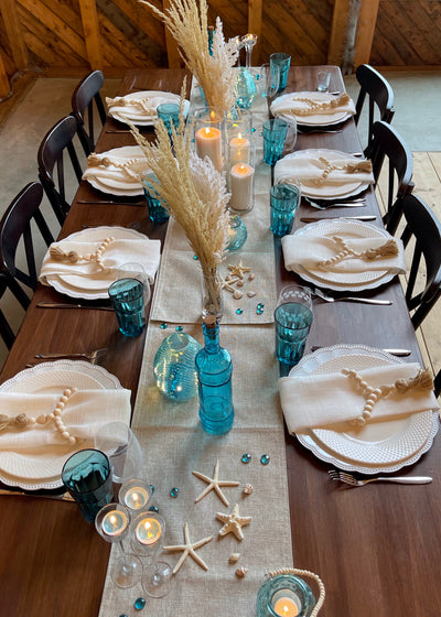 Beach themed table scape with teal glass ware and pamps and wheat glass  in a champaign flute serving as a simple elegant centrepiece.
