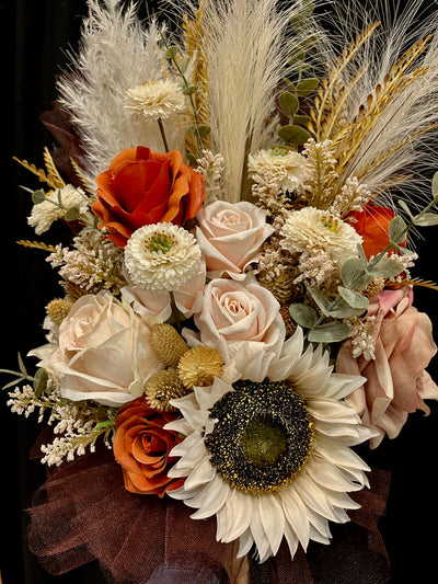 Rent A Rose- This side held bouquet combines ivory, cappuccino, and rust roses, with cream sunflowers, mini dahlia, pampas, feathers, wheat grass, thistle and sage eucalyptus to create a  relaxed natural bohemian vibe.