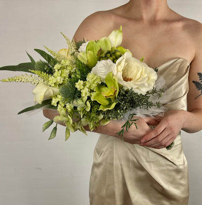 This crisp white bridesmaid bouquet combines white roses, astilbe and dark green ivy to create a simple elegant bouquet. It is finished off with a wispy white tulle base and a white satin wrapped handle. Five day rental $69.00